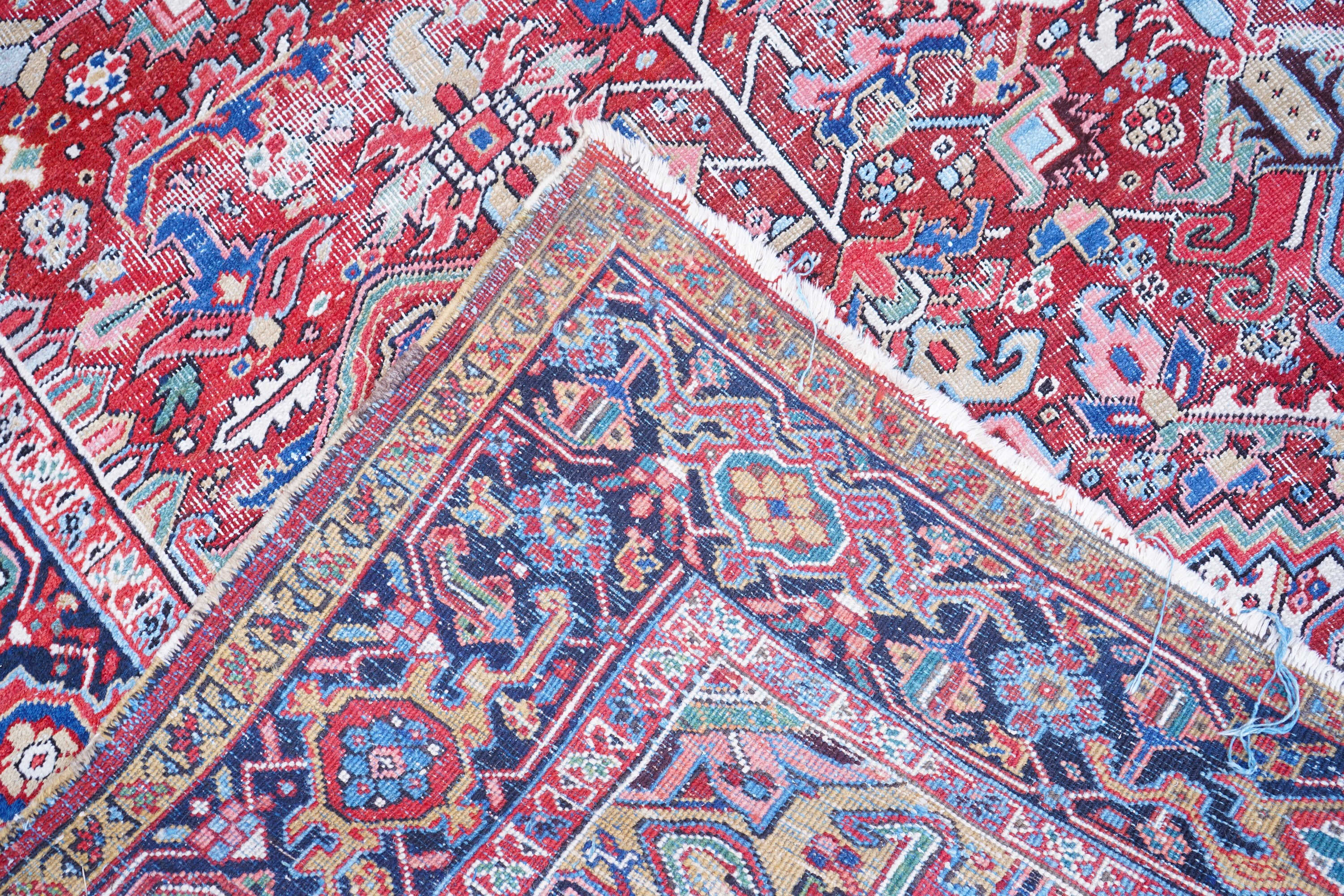 An antique Heriz brick red ground carpet with central